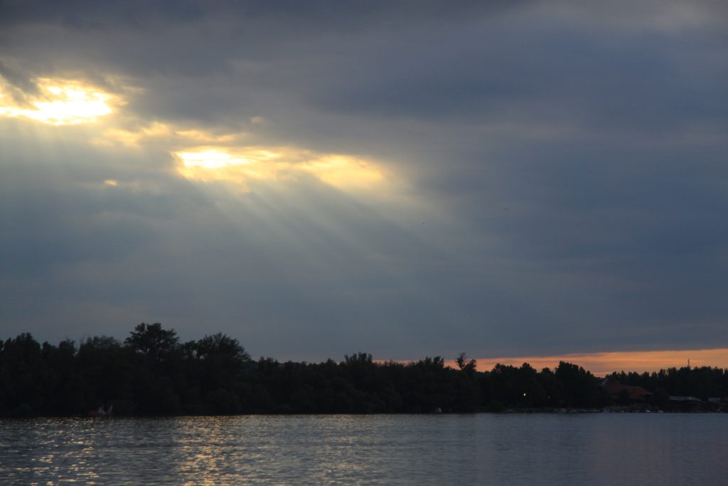 Sunshine through clouds dark sky river before storm