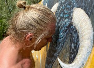 Artis t showing compassion, gently touching the head of a bull in a moment of connection and understanding. This image relates to themes explored in the "Crime Scene" provocative bull painting.