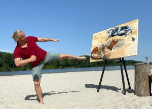 Artist demonstrates karate move in front of the "Karate Bull" surreal flying bull painting, mimicking the bull's pose.